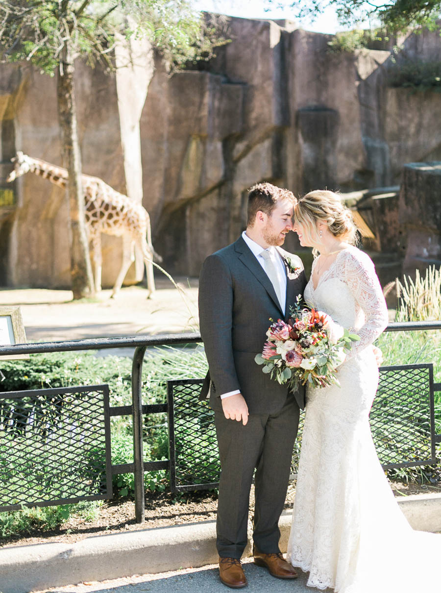 bride and groom portrait with giraffe, glamping and chic safari romantic outdoor wedding at Milwaukee County Zoo, Wisconsin, photo by Laurelyn Savannah Photography