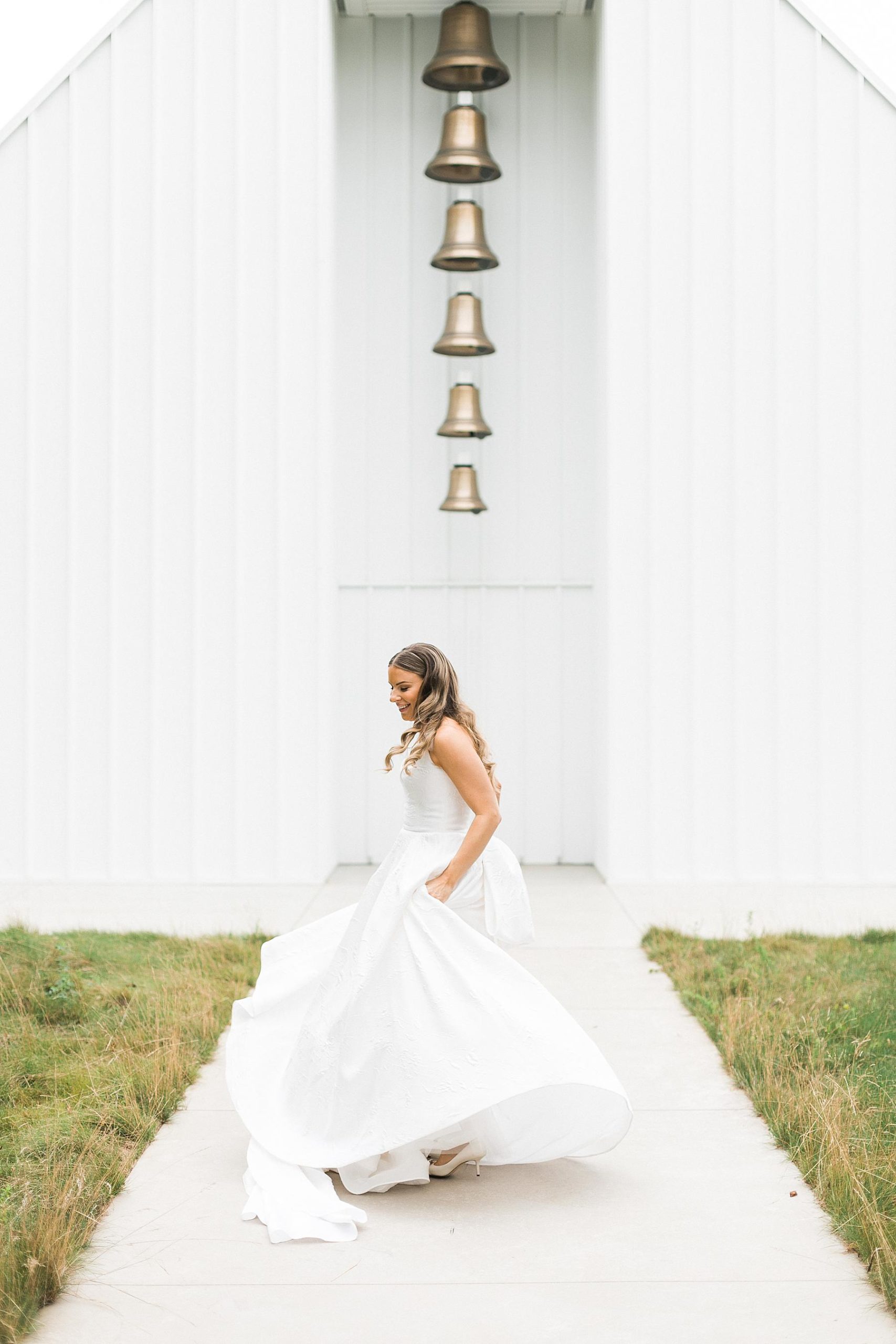 bride in front of traditional white chapel for wedding ceremony at straits chapel in kohler wisconsin