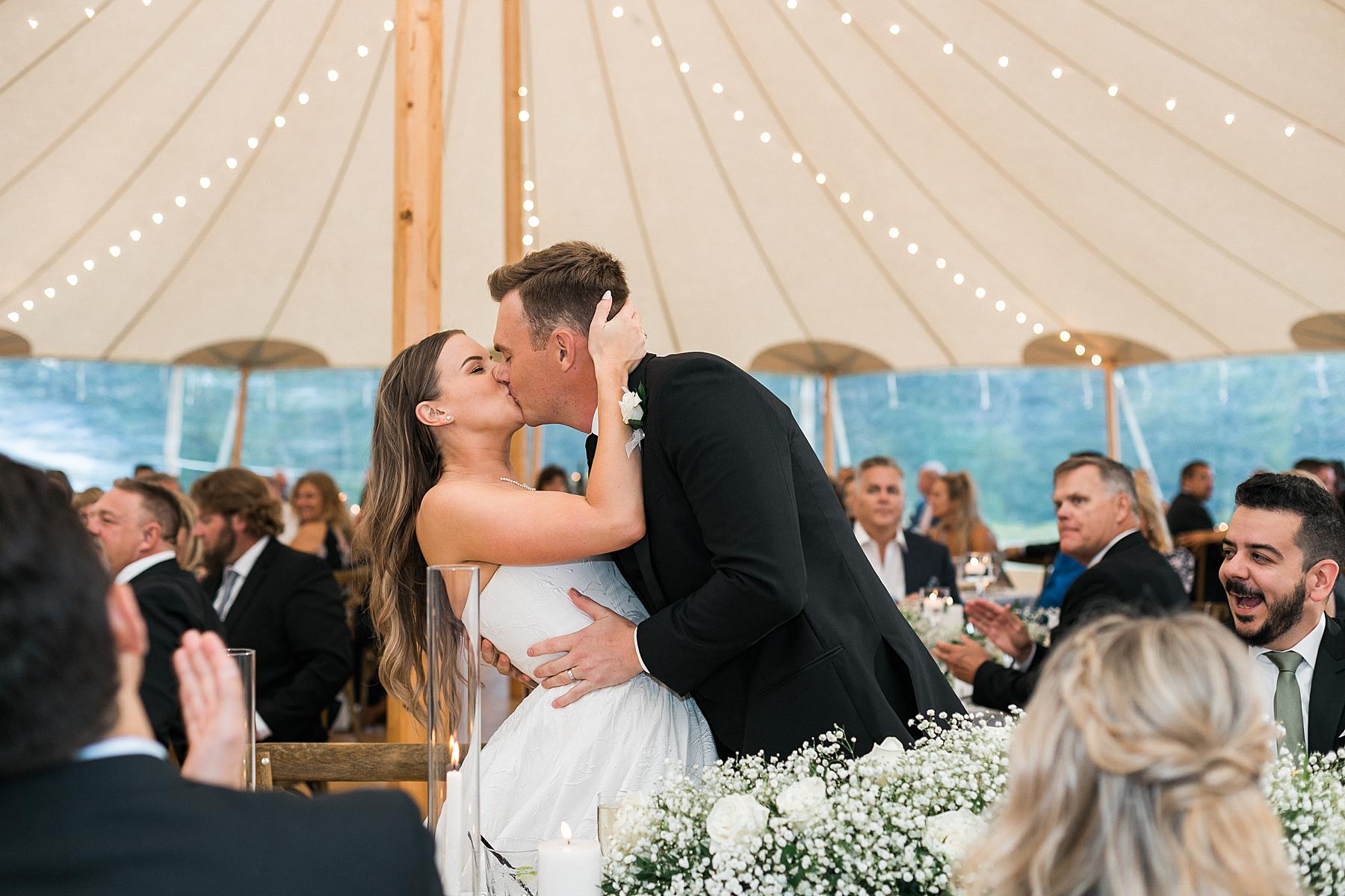 dinner reception and newlyweds kissing at irish barn at whistling straits in kohler wisconsin