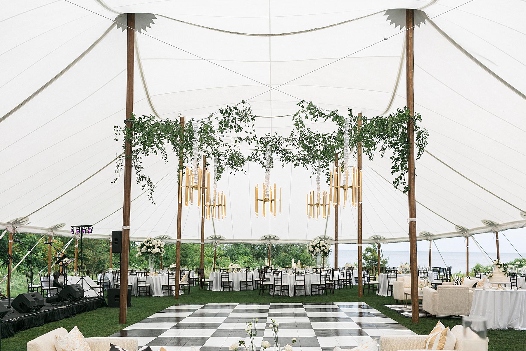 checkerboard dance floor and hanging chandelier under sailcloth tent wedding reception at horseshoe bay beach club in door county