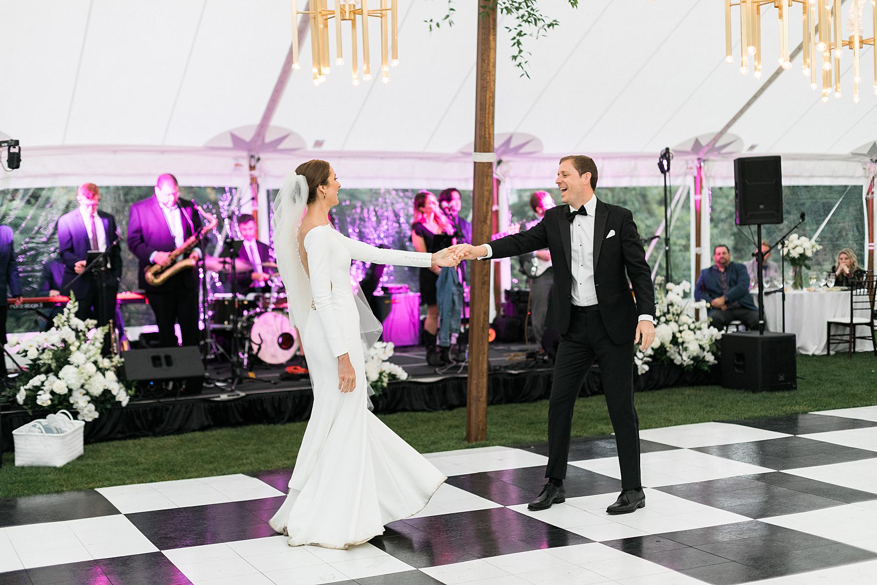 newlyweds first dance on checkerboard dance floor under a sailcloth tent wedding reception with live band, at horseshoe bay beach club in door county