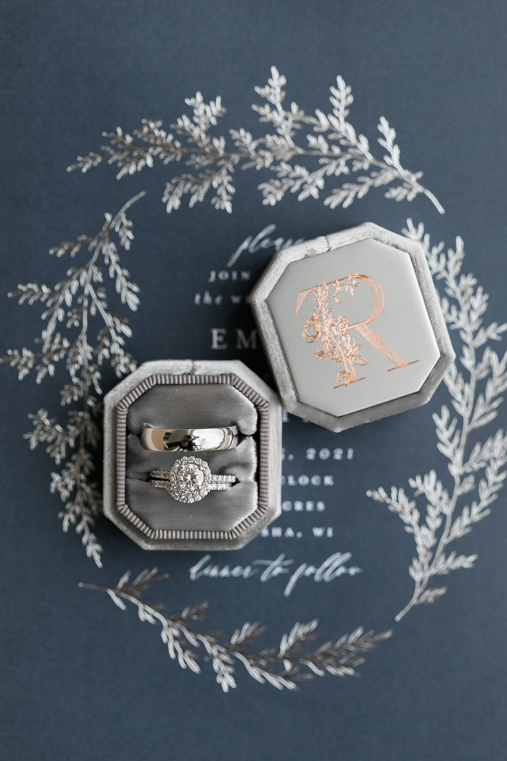 wedding rings bands on top of navy blue wedding invitation