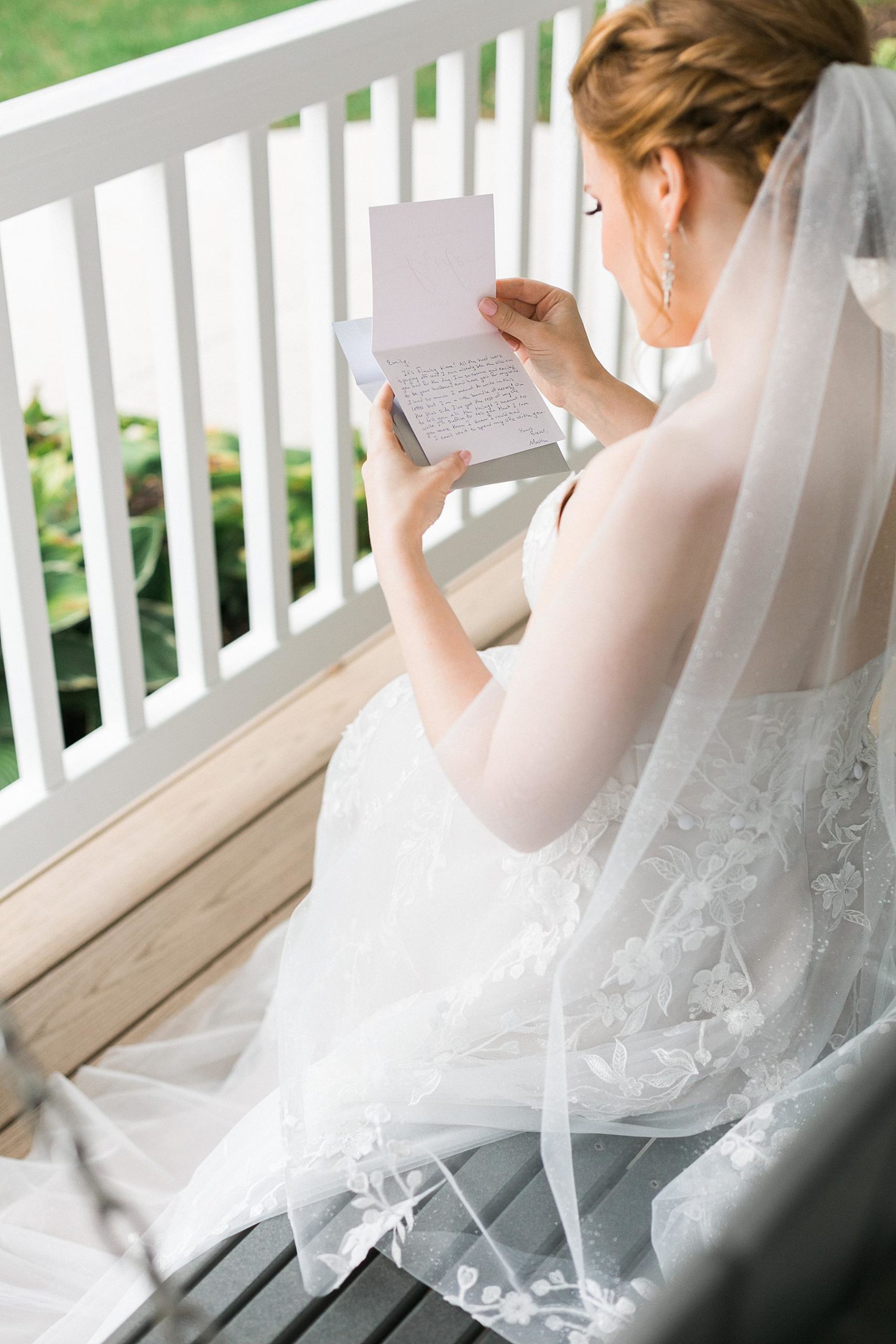 bride in wedding gown dress reading a letter from the groom on farmhouse front porch