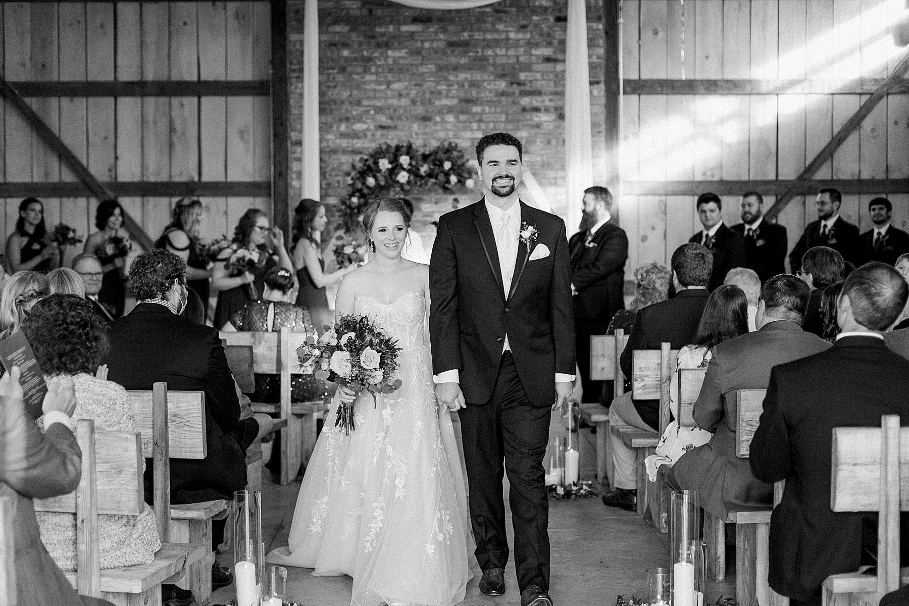 newlywed couple exit at indoor barn wedding ceremony at lilac acres in milwaukee, wisconsin