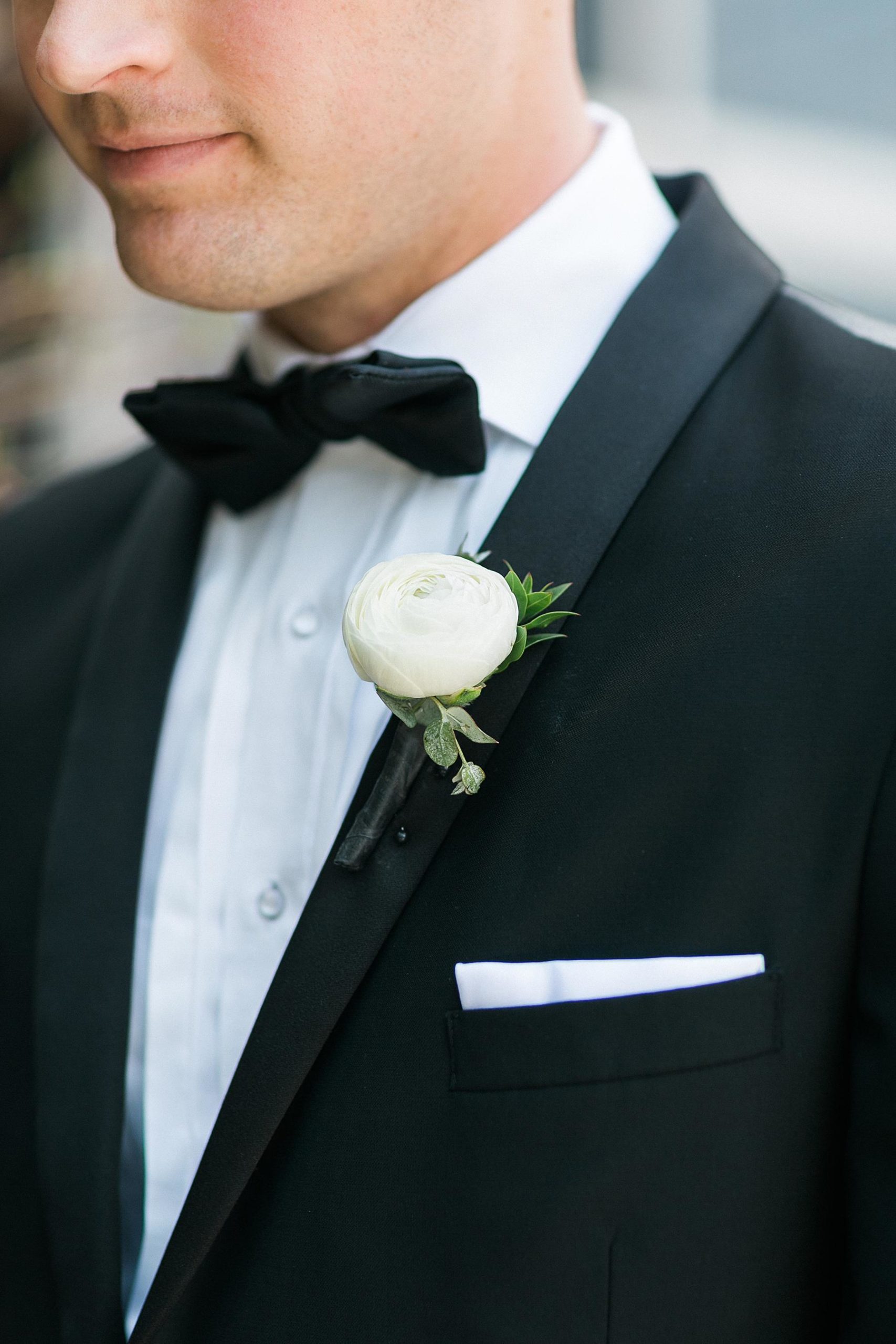 groom bout flower on lapel on black suit