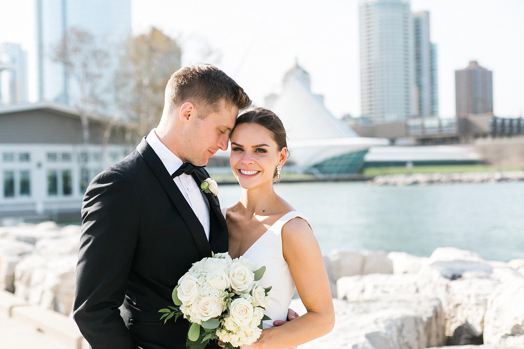 bride and groom couple newlywed portraits along the lakefront art museum and city skyline in downtown milwaukee, wi