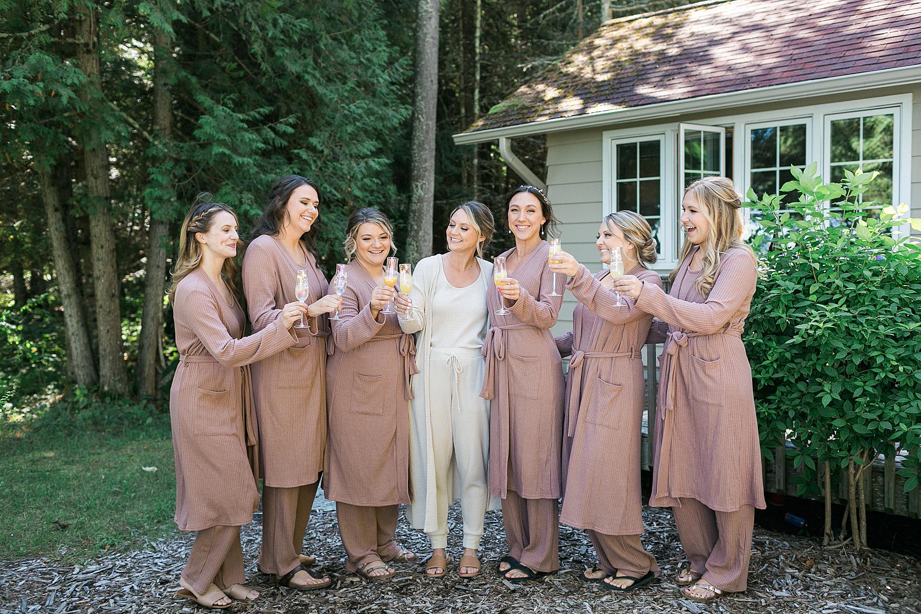 bride and bridesmaids toasting champagne in getting ready robes in front of cabin at gordon lodge in door county