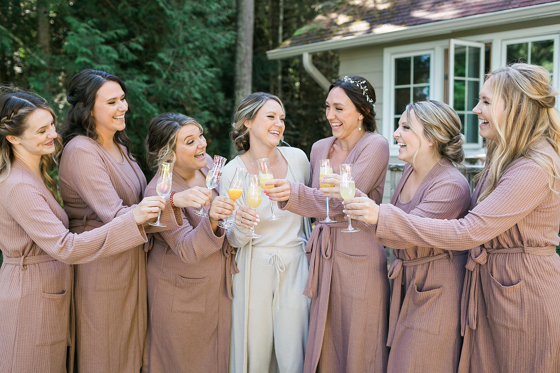 bride and bridesmaids toasting champagne in getting ready robes in front of cabin at gordon lodge in door county