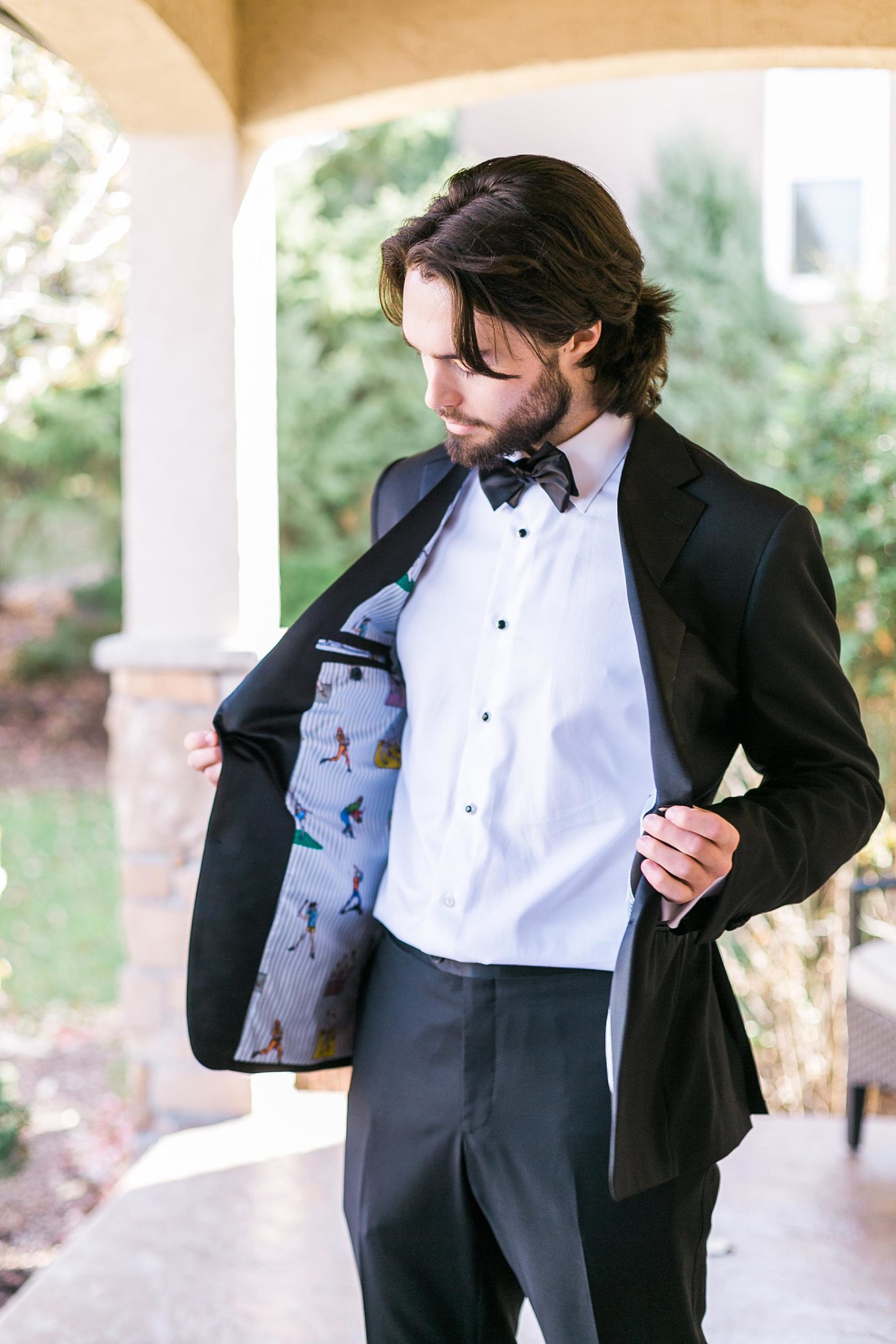 groom putting on suit jacket on a front porch