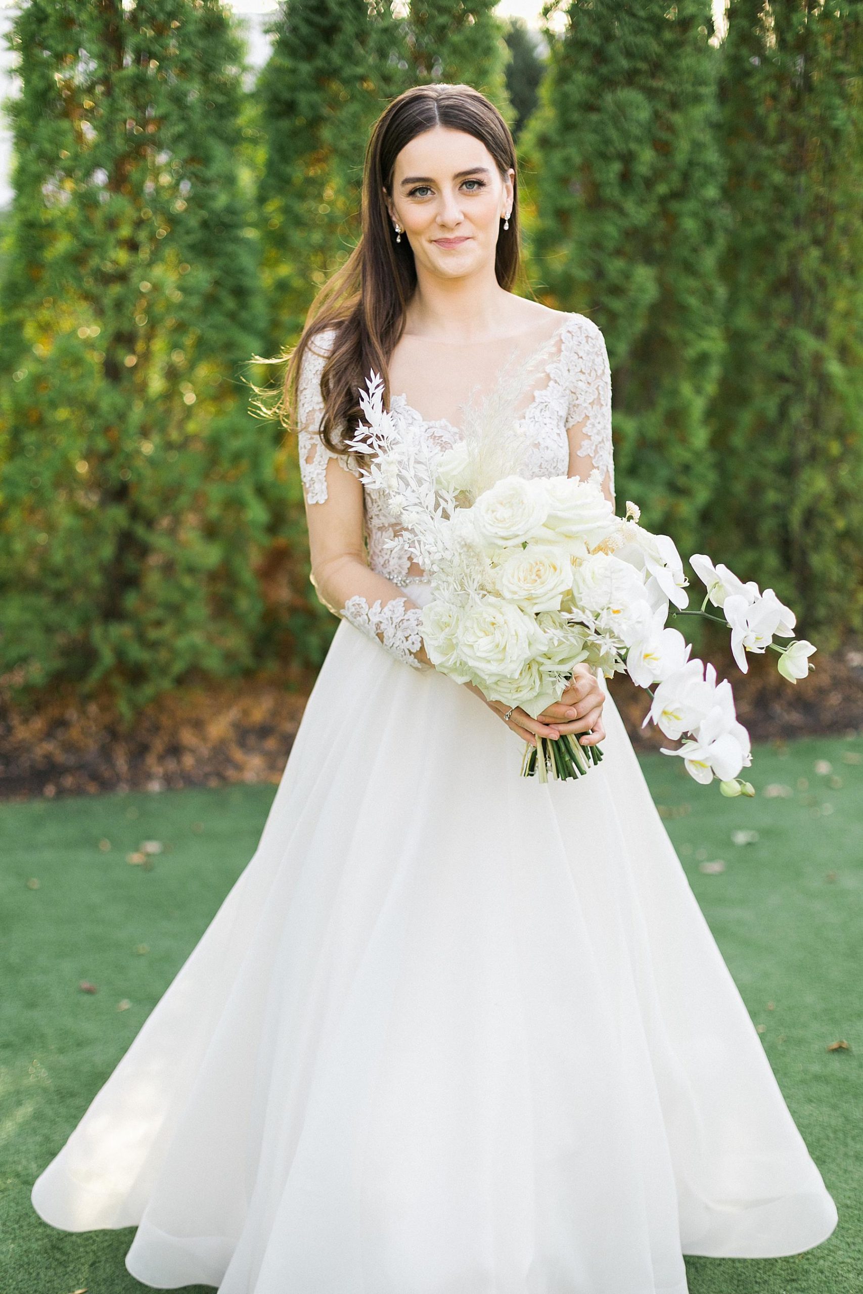bride with lace long sleeved gown dress holding white boho loose bouquet