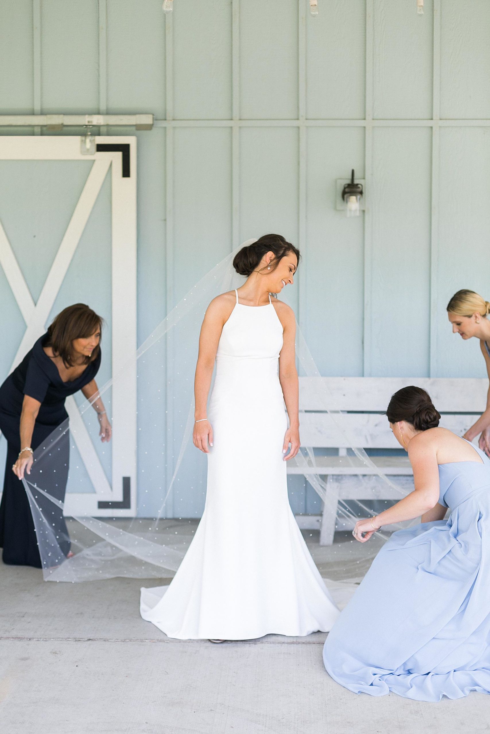 bride getting dressed with blue barn in the background