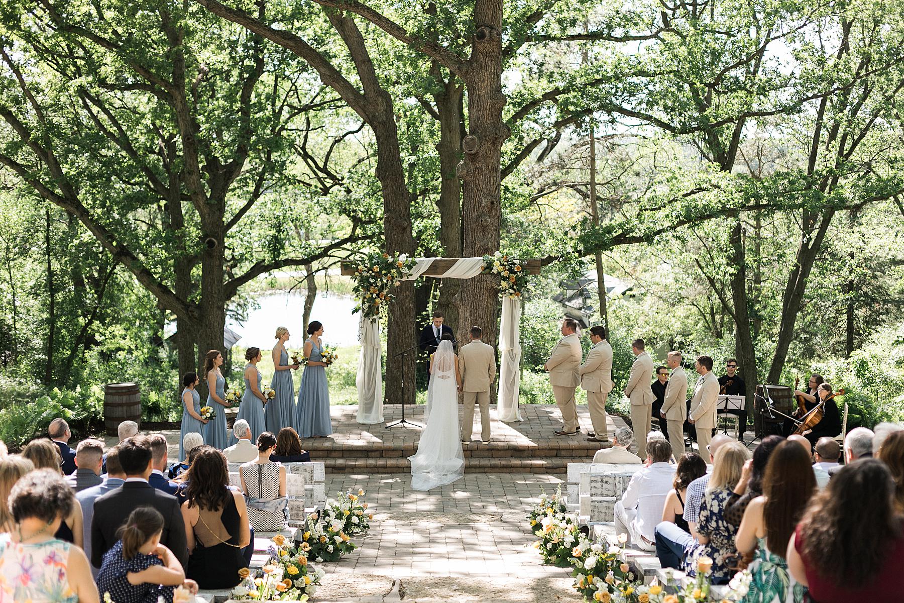 refined elegant outdoor wedding ceremony, with orange and yellow flowers and blue dresses, fields reserve near madison, wisconsin