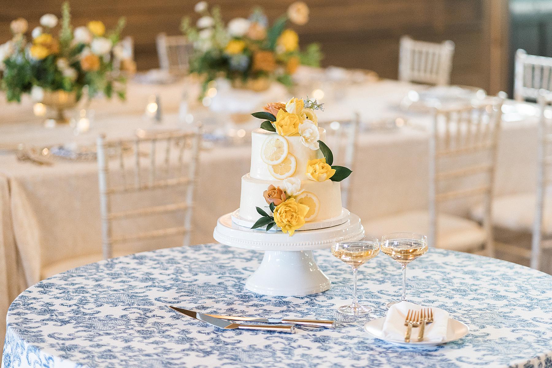 wedding cake at refined upscale barn wedding reception decor with yellow, orange, and blue florals near madison, wisconsin