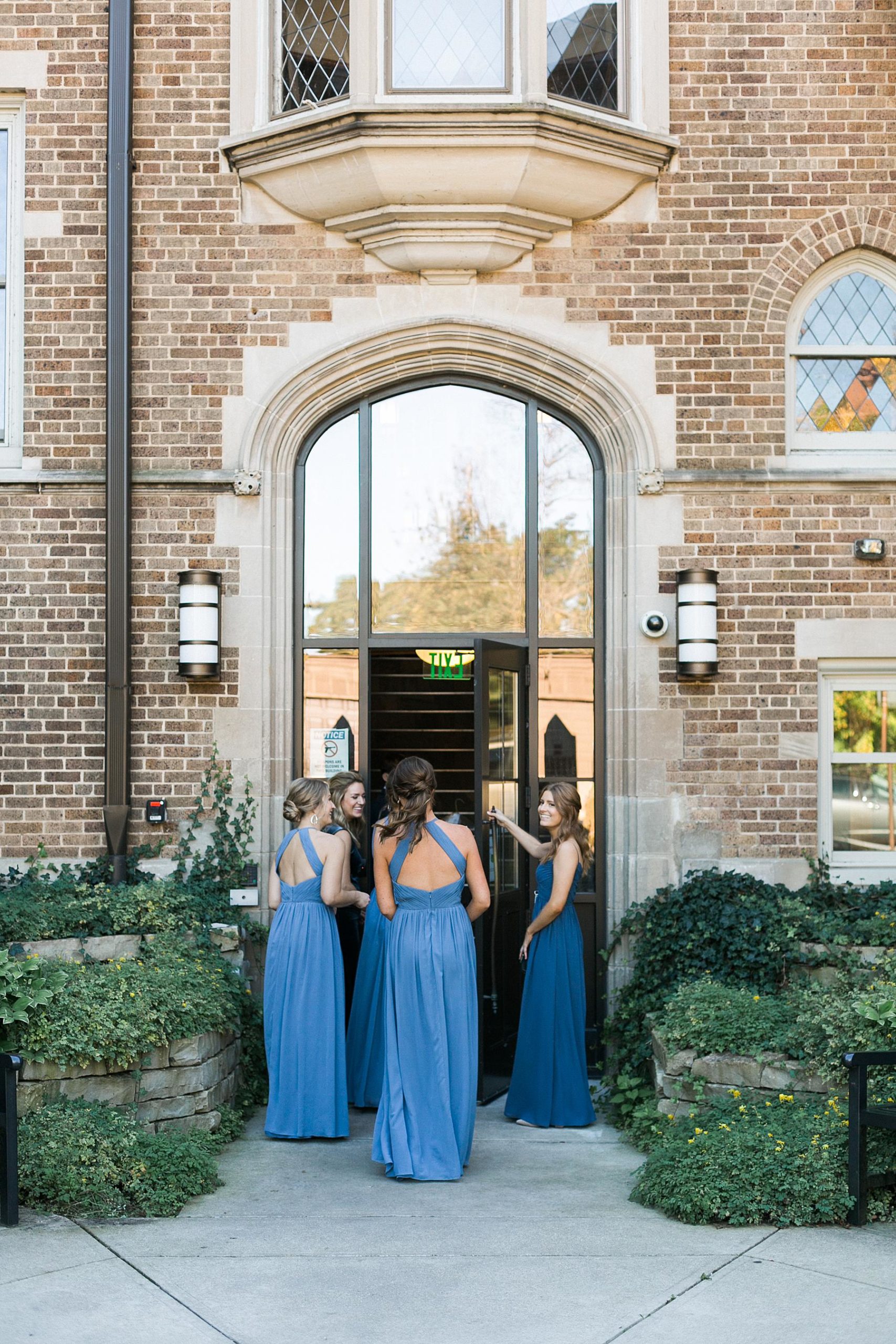 bridesmaids in blue velvet and chiffon dresses entering church for wedding ceremony