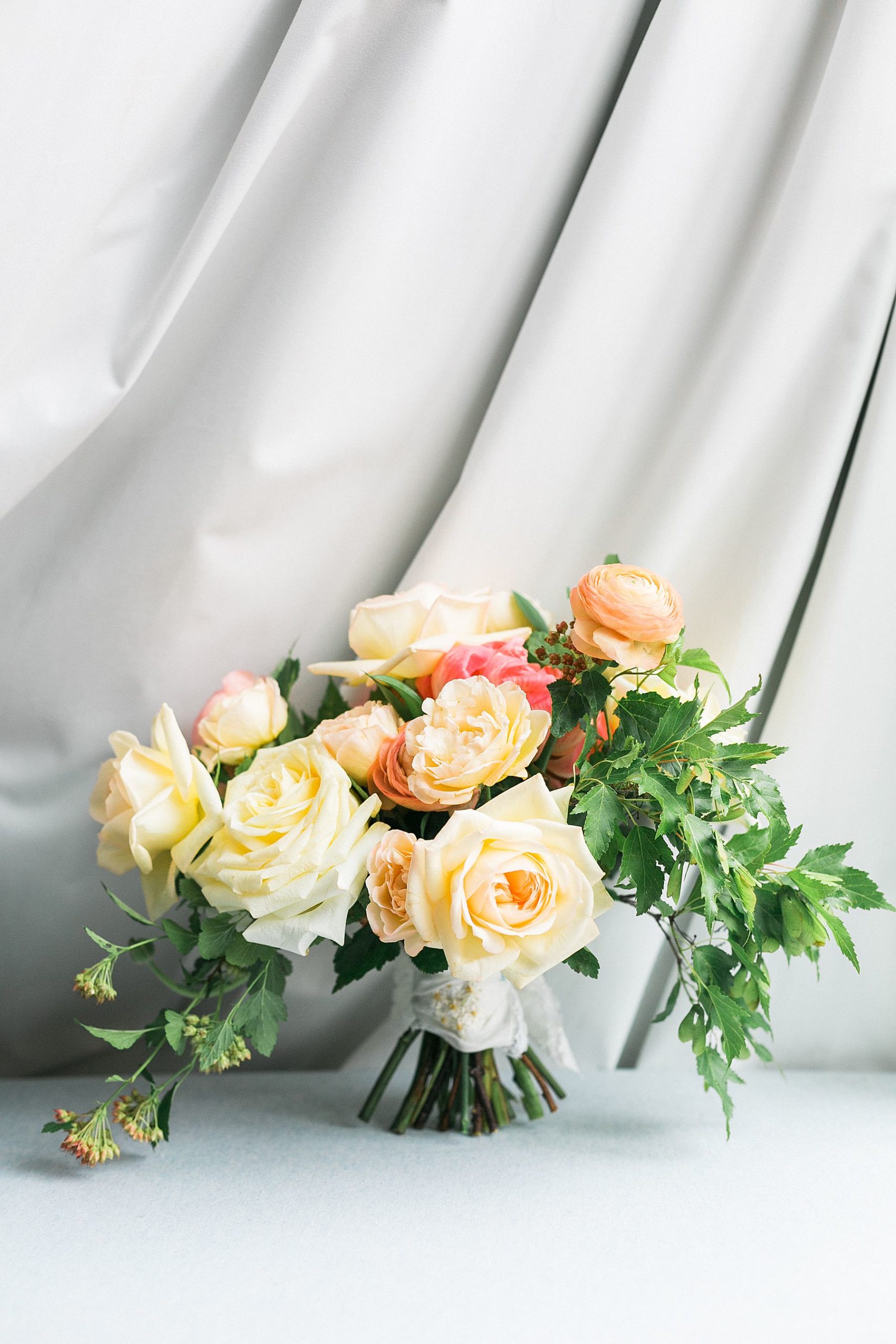 bridal wedding garden style bouquet of pastel coral and orange and yellow flowers for modern elegant wedding